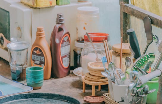 Close-up of a cluttered kitchen counter with utensils, jars, and a Hershey's syrup bottle.
