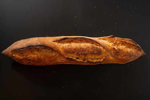 Close-up of a freshly baked artisan baguette displayed on a dark surface.